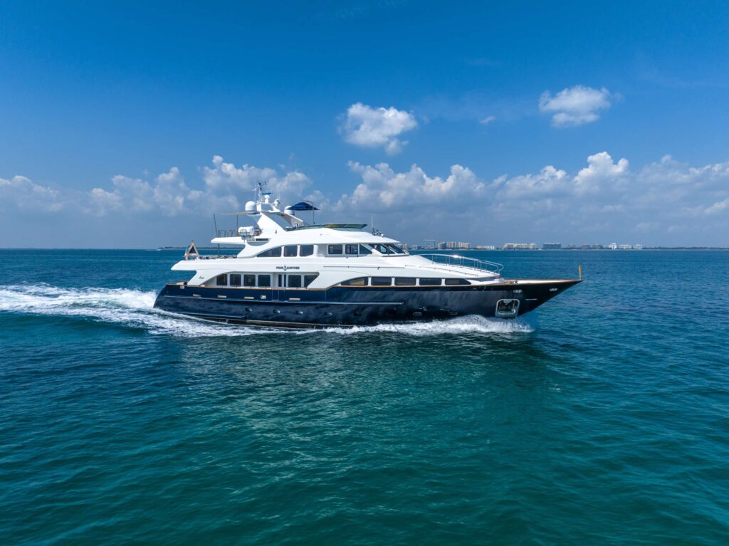 Elegant 7499 superyacht approaching picturesque coastline.