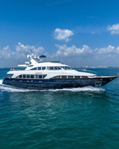 Elegant 7499 superyacht approaching picturesque coastline.